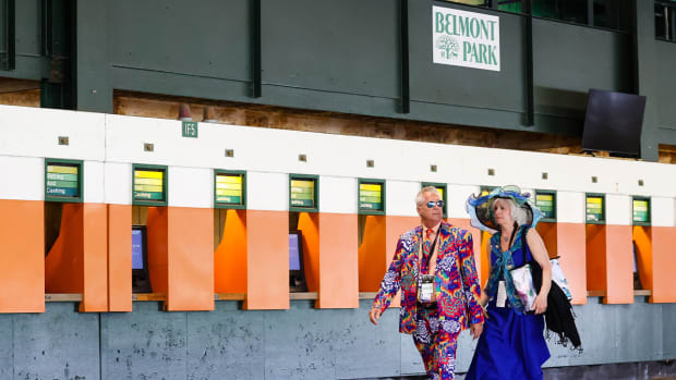 Jun 11, 2022; Elmont, NY, USA; Two horse racing fans walk by the betting station at Belmont Park Racetrack.